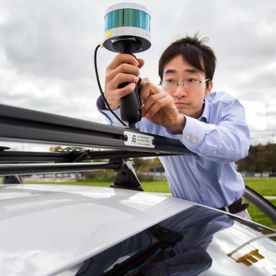 Researcher Attaching a device to the roof of an autonomous vehicle